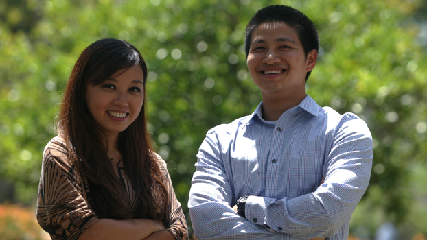 A Asian woman and an Asian man stand next to each other with arms crossed.