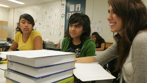 two young students with a woman listening to a lesson.