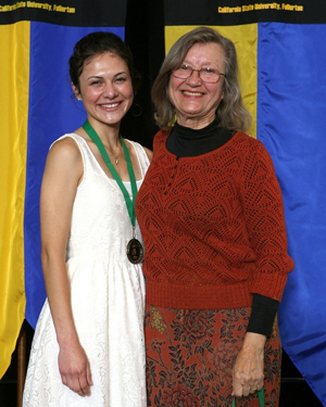 A college student stands beside her faculty mentor.