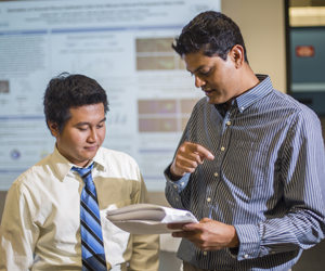 Two men look over research material.