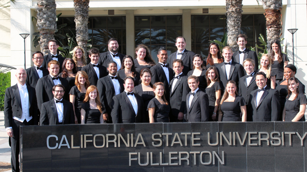 Large group of singers in black dresses and tuxedos.