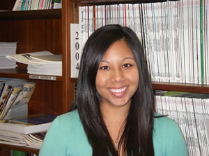 Young Asian woman sitting in front of a bookcase filled with journals.