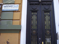 Door with detailed wood relief carving and inlaid-glass windows set into a stone facade building.