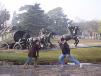 Doreen and a companion pose in front of a monument of a horse-drawn carriage