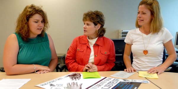 Program and center leaders discuss promotional materials at a conference table.
