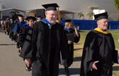 Faculty make their way towards the ceremonies wearing caps and gowns
