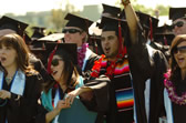 Commencement candidates in caps and gowns cheer during commencement ceremonies